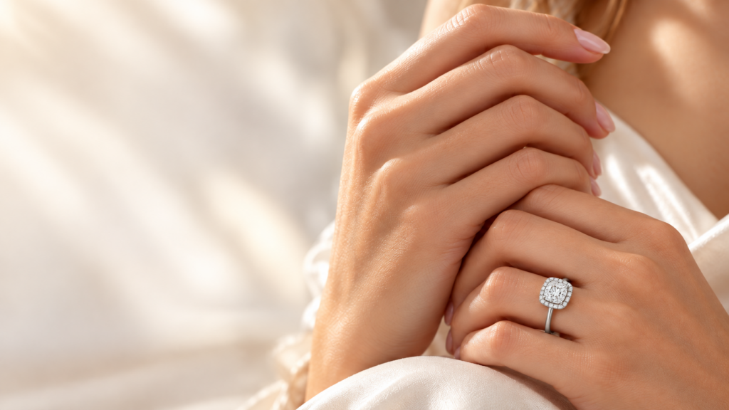 Cushion halo engagement ring in white gold worn on the hand