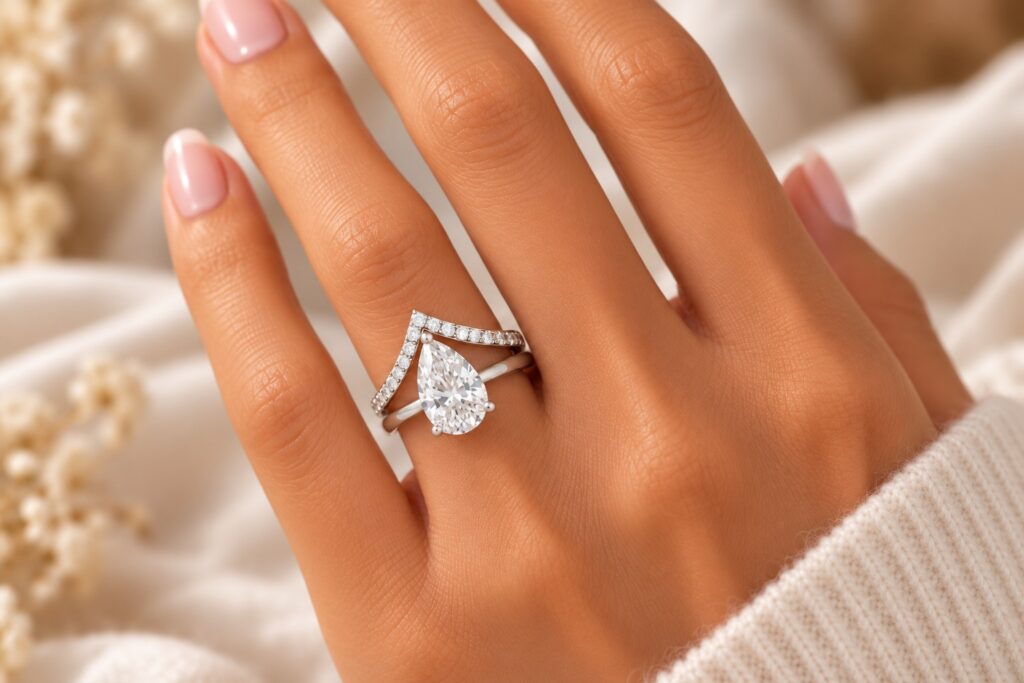 Pear natural diamond solitaire and wishbone diamond wedding band in white gold worn on the hand